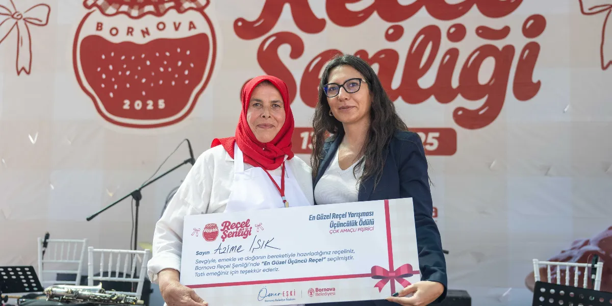 Kırmızı başörtülü ve beyaz önlüklü bir kadın ile yanında duran gözlüklü bir kadın, Bornova Reçel Şenliği kapsamında düzenlenen En Güzel Reçel Yarışması'nda verilen üçüncülük ödülünü birlikte tutuyor. Ödül belgesinde 