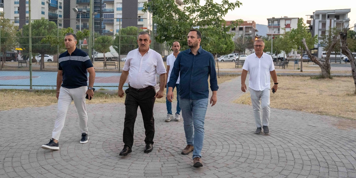 Bornova Doğanlar mahallesindeki bir parkta yürüyen dört erkek, incelemelerde bulunuyor. Önde solda lacivert polo yaka tişörtlü ve açık renk pantolonlu bir kişi, yanında beyaz gömlekli ve siyah pantolonlu bir kişi, onun arkasında beyaz tişörtlü bir kişi ve sağ tarafta lacivert gömlekli, kot pantolonlu bir kişi yer alıyor. Arka planda basketbol sahası, ağaçlar ve yerleşim yerleri görülüyor.