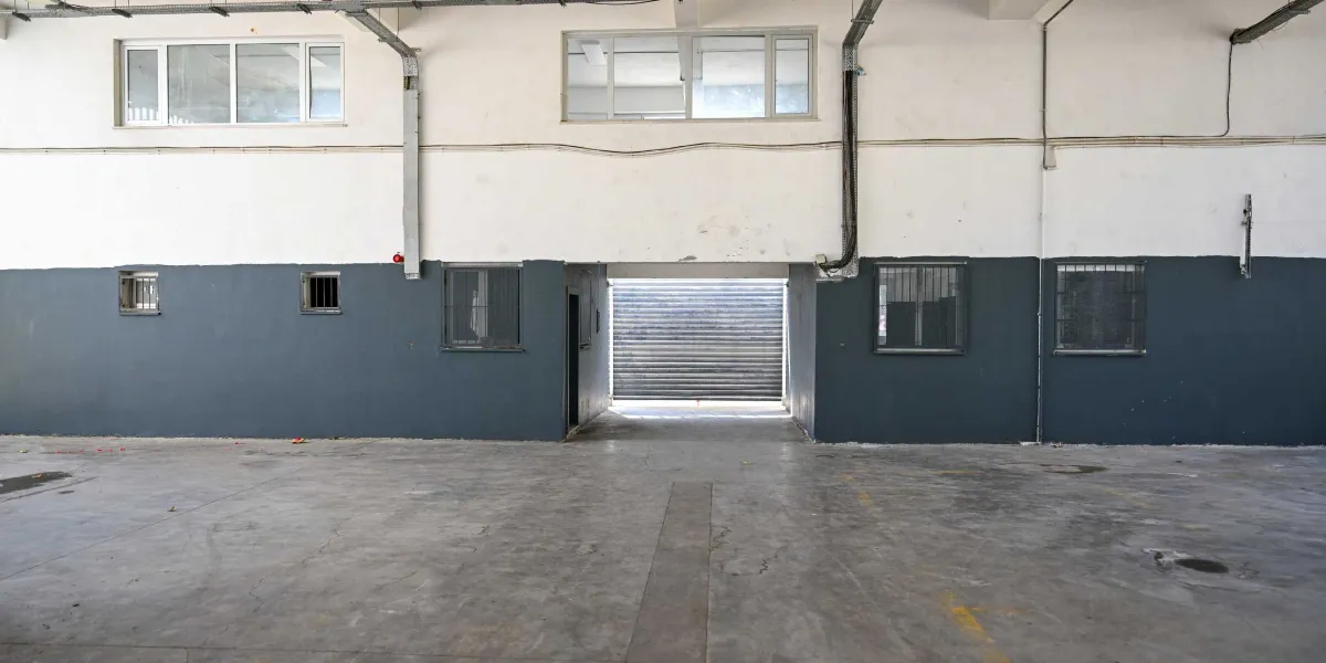 Beton zeminli, geniş ve boş bir kapalı pazar alanı. Duvarların alt kısmı koyu griye boyanmış, üst kısımları ise beyaz bırakılmıştır. Duvarlarda demir parmaklıklı küçük pencereler ve üst bölümde daha büyük pencereler bulunur. Ortada, dışarıya açılan kapalı bir kepenk sistemi yer almaktadır.