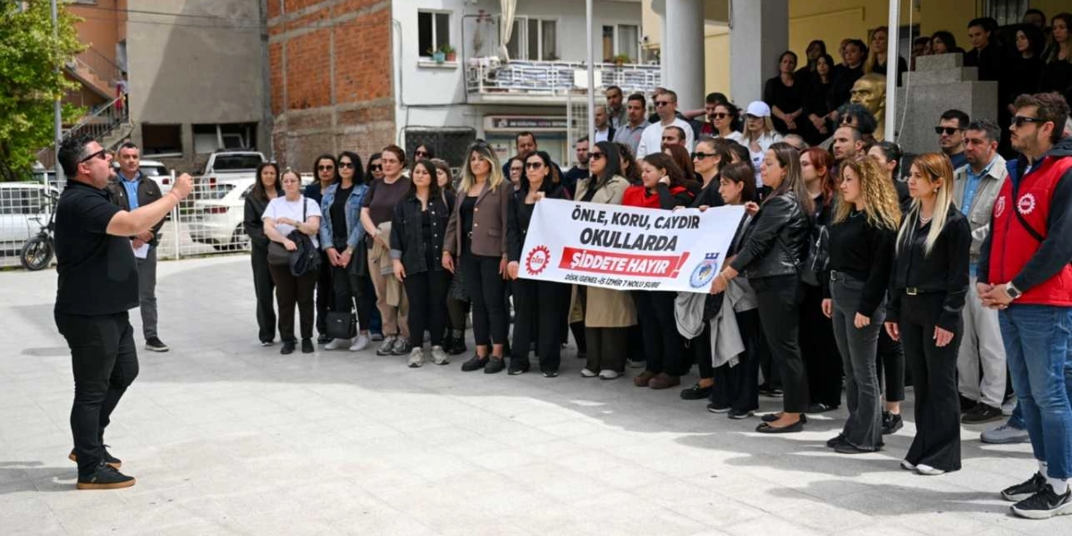 Açık havada, bir okul bahçesinde toplanmış kalabalık bir grup, üzerinde 