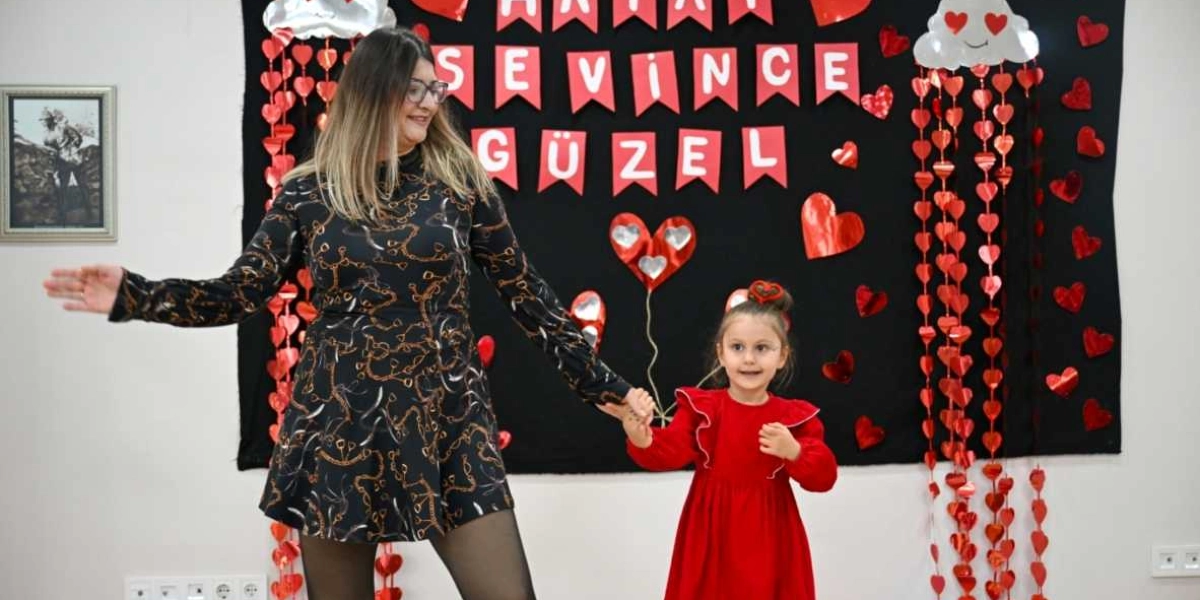 Siyah desenli bir elbise giyen bir kadın ile kırmızı elbiseli küçük bir kız çocuğu, üzerinde 