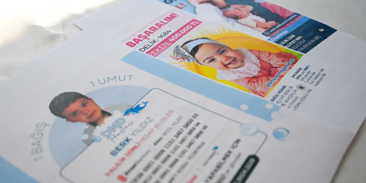 SMA hastası çocuklar için hazırlanan yardım kampanyası broşürleri. Ön planda Berk Yıldız'ın, arka planda ise Esma Gönültaş'ın fotoğraflarının yer aldığı, bağış hesap numaraları ve SMS bilgilerini içeren bilgilendirme kağıtları.