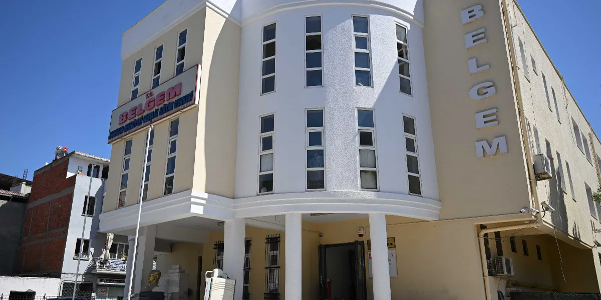 Açık sarı ve beyaz renkli, modern mimariye sahip BELGEM binasının dış görünüşü. Binanın girişinde beyaz sütunlar bulunuyor ve cephesinde kırmızı harflerle 