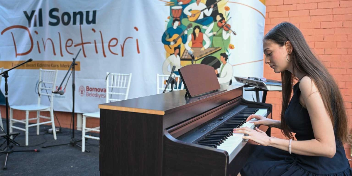 Uzun saçlı genç bir kadın, üzerinde Yıl Sonu Dinletileri yazan bir pankartın önünde, tuğla duvarlı bir açık hava sahnesinde dijital piyano çalıyor. Arka planda çeşitli müzik aletleri çalan insan figürlerinin olduğu bir illüstrasyon ve Bornova Belediyesi logosu yer alıyor.