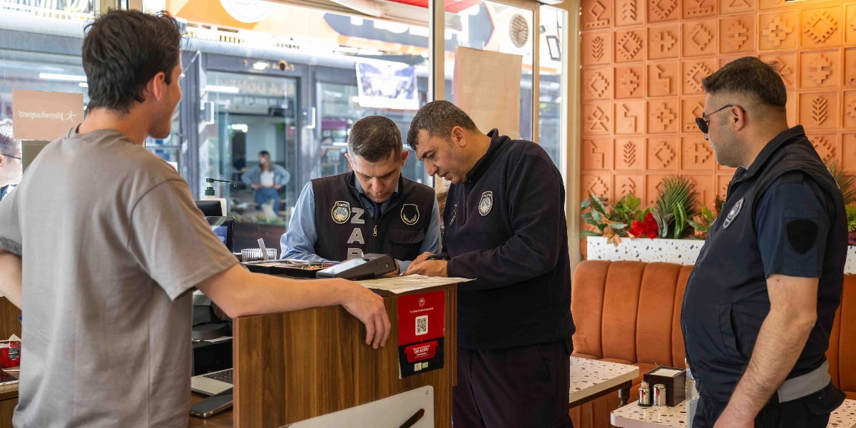 Bornova Belediyesi zabıta ekipleri, bir işletmede dijital denetim gerçekleştiriyor. Üzerlerinde 