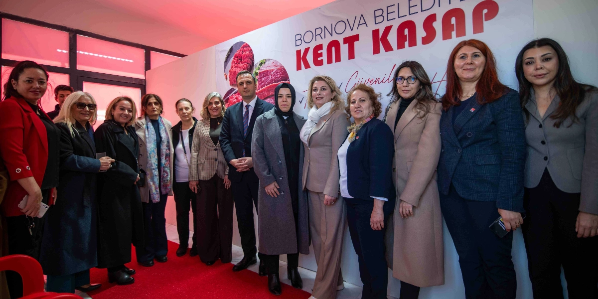 Bornova Belediyesi Kent Kasap yazılı pankartın önünde, aralarında CHP Kadın Kolları Başkanı Asu Kaya ve Bornova Belediye Başkanı Ömer Eşki'nin de bulunduğu, resmi kıyafetli bir grup kadın ve erkek yan yana durarak poz veriyor.