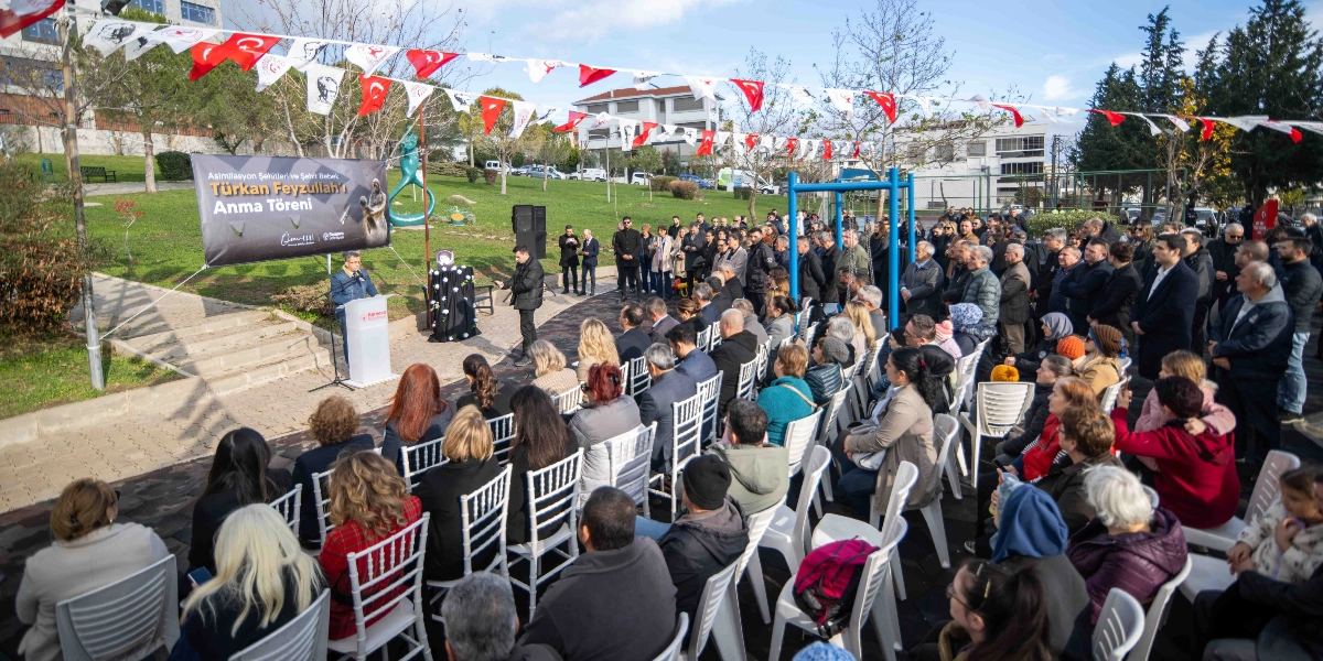 Bornova'da düzenlenen Türkan Feyzullah'ı anma töreninde, açık havada kurulan beyaz sandalyelerde oturan kalabalık bir topluluk, kürsüde konuşma yapan kişiyi dinliyor. Alanın üzerinde Türk bayrakları ve Atatürk silüetlerinin bulunduğu flamalar asılı. Kürsünün yanında üzerinde 