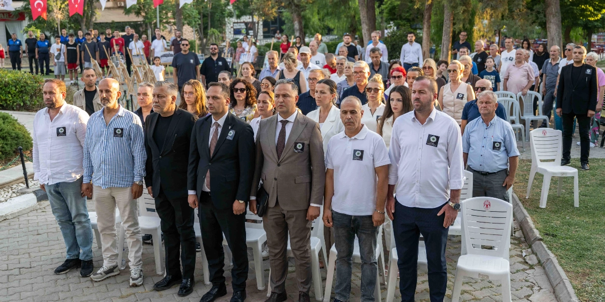 Açık havada, park benzeri bir alanda düzenlenen anma töreninde, yakalarında Srebrenitsa soykırımını simgeleyen 