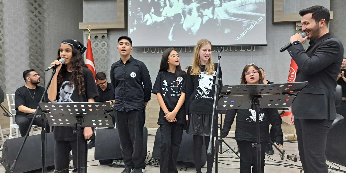 Kapalı bir sahnede, üzerinde Atatürk baskılı siyah tişörtler giyen dört çocuk ve onlara eşlik eden bir yetişkin şarkı söylüyor. Çocuklardan biri mikrofon tutarken, diğerleri yan yana duruyor ve bir yetişkin de sağ tarafta elinde mikrofonla onlara katılıyor. Sahnenin arka planında Bornova Belediyesi yazılı bir duvar ve üzerinde Atatürk'ün olduğu siyah beyaz bir projeksiyon yansıtılıyor. Sahnenin sol tarafında bir müzisyen klavye başında oturuyor, önlerinde ise nota sehpaları bulunuyor.