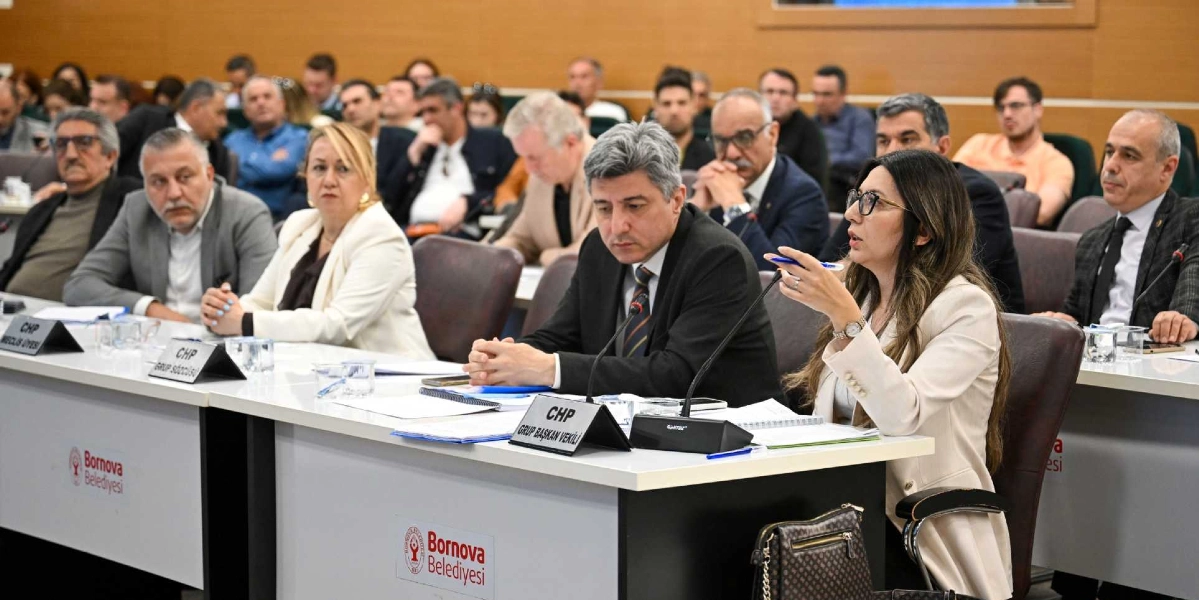 Bornova Belediyesi meclis toplantı salonunda, masada oturan ve üzerinde 