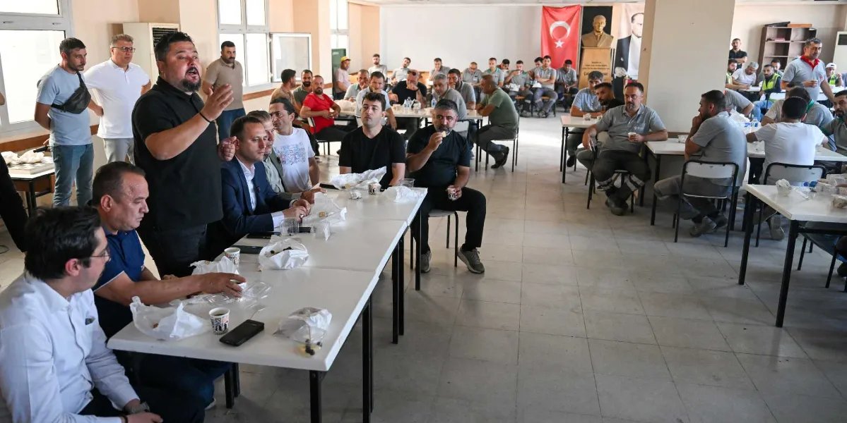 Belediye başkanı olduğu anlaşılan siyah tişörtlü bir kişi, bir yemekhanede masalarda oturan itfaiye personeline hitaben konuşma yapıyor. Uzun beyaz masaların etrafında oturan çok sayıda çalışan, önlerindeki yemek kapları ve içeceklerle birlikte konuşmayı dinliyor. Arka planda duvarda asılı bir Türk bayrağı ile Mustafa Kemal Atatürk'ün büstü ve portresi yer alıyor.