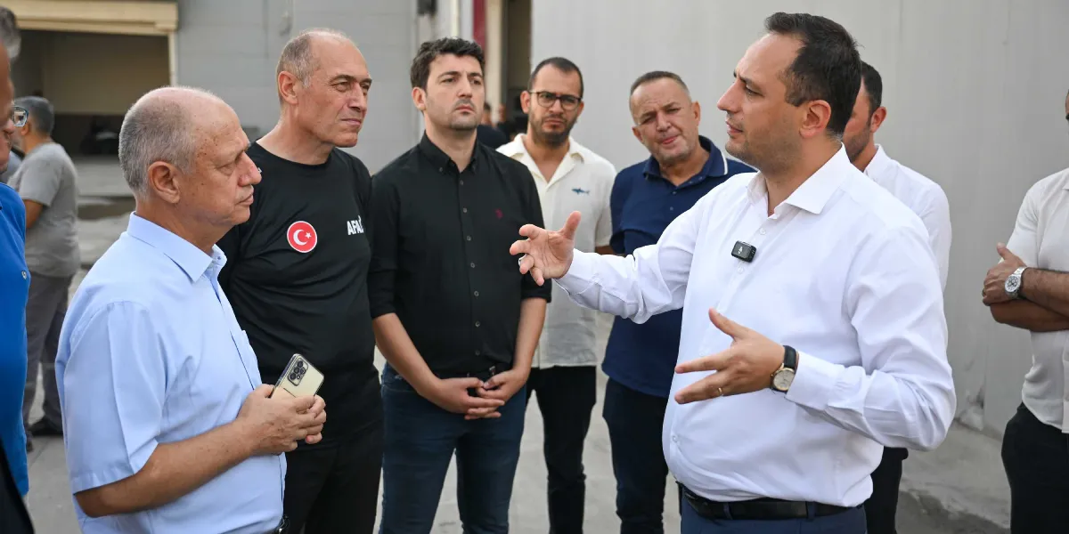 Beyaz gömlekli bir yetkilinin, aralarında üzerinde AFAD yazılı siyah tişörtlü bir kişinin de bulunduğu bir grup erkeğe açıklama yaptığı toplantı anı.