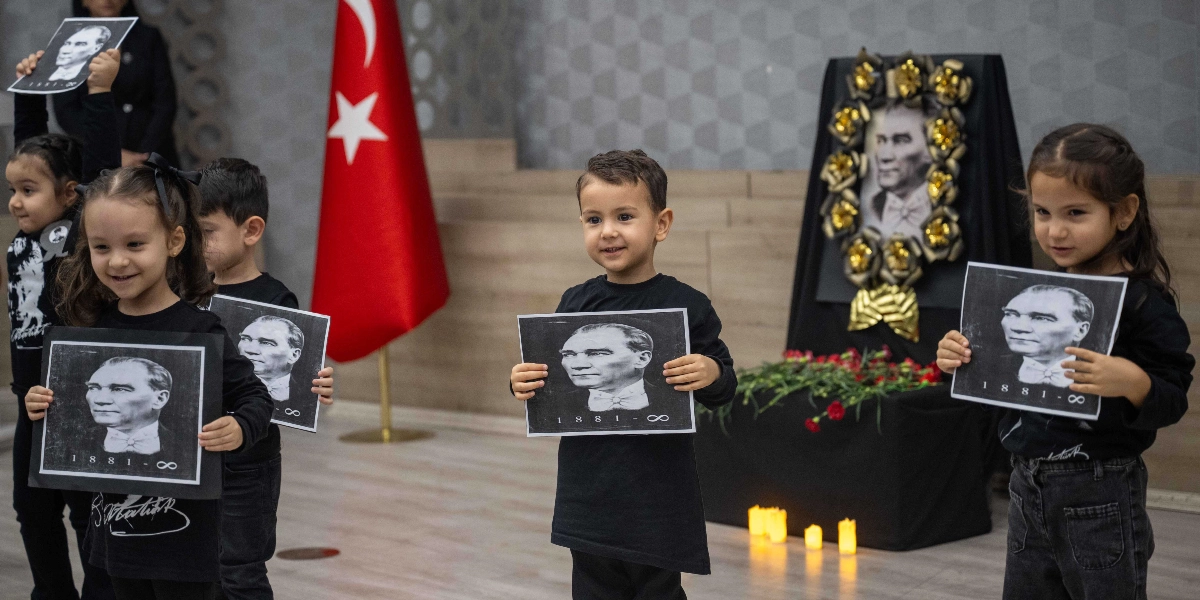 Siyah kıyafetler giymiş anaokulu çağındaki çocuklar, ellerinde üzerinde Mustafa Kemal Atatürk'ün fotoğrafı ile 
