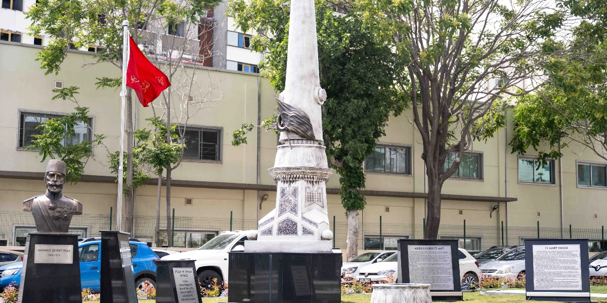 Bornova'da bulunan Adalet ve Hürriyet Anıtı'nın önünde, sol tarafta Mahmut Şevket Paşa'nın büstü ve yanında Osmanlıca yazılı kırmızı bir bayrak yer alıyor. Anıtın sağ tarafında ise 31 Mart Vakası ve Adalet-i Hürriyet Anıtı hakkında bilgilendirme metinlerinin bulunduğu iki ayrı tabela bulunuyor. Arka planda ağaçlar, park halindeki araçlar ve modern bir bina yapısı görülüyor.