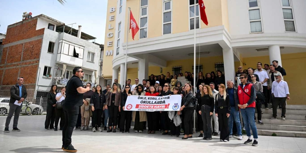 Bornova Belediyesi BELGEM binası önünde toplanan kalabalık bir grup, okullarda şiddete karşı protesto düzenliyor. Grubun önünde yer alan kişiler, üzerinde 
