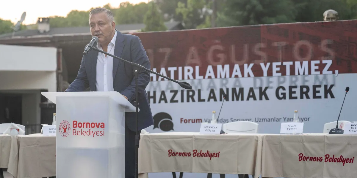 Bornova Belediyesi tarafından düzenlenen afet bilinci buluşmasında, kürsüde konuşma yapan bir yetkili görülüyor. Arkasındaki büyük panoda 